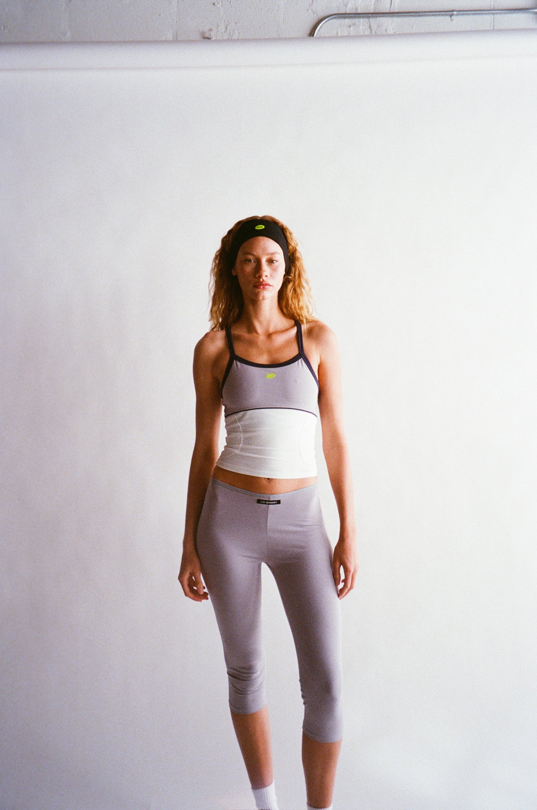 Woman in athletic wear standing against a white wall |M1
