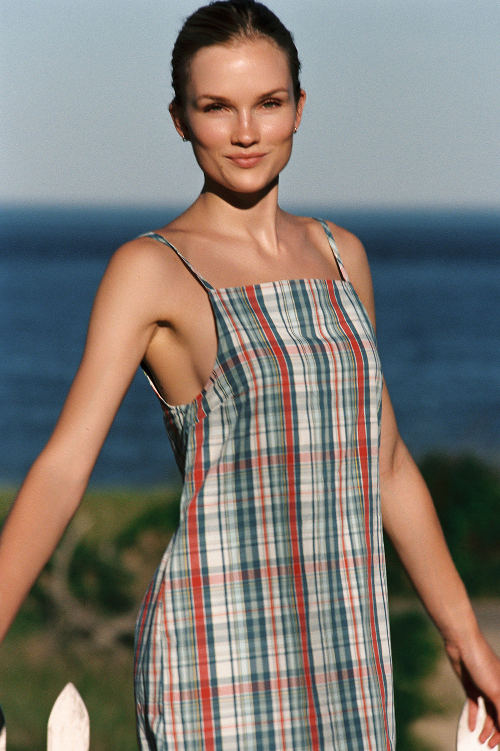 Woman wearing a plaid dress standing by the ocean