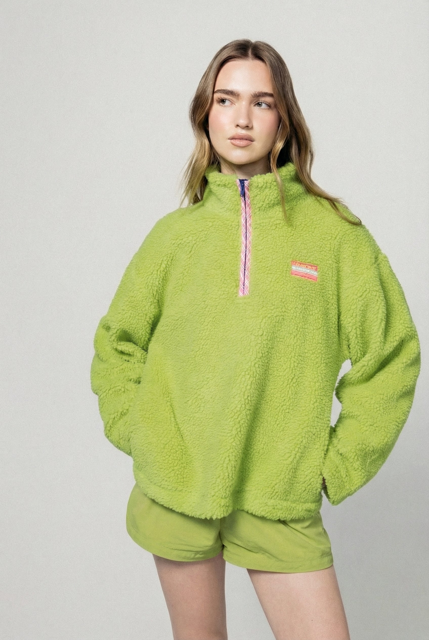 Person wearing a bright green fleece outfit with a small logo on a light gray background |m1