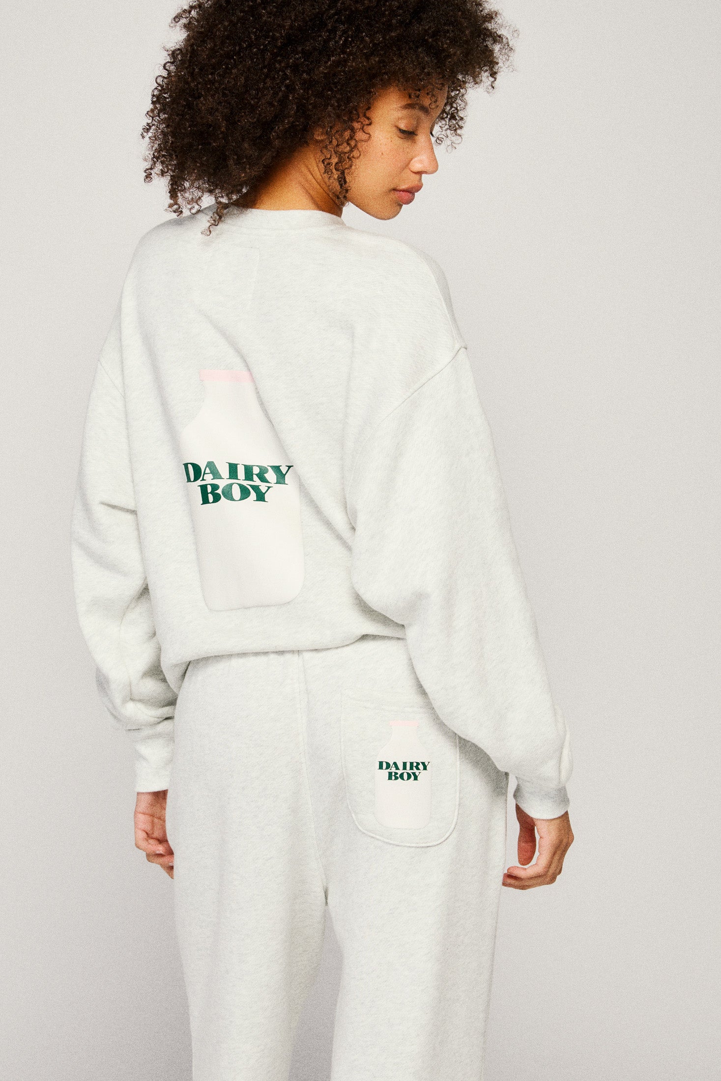 Person wearing a light grey sweatshirt and pants with 'Dairy Boy' branding on a plain background |m1