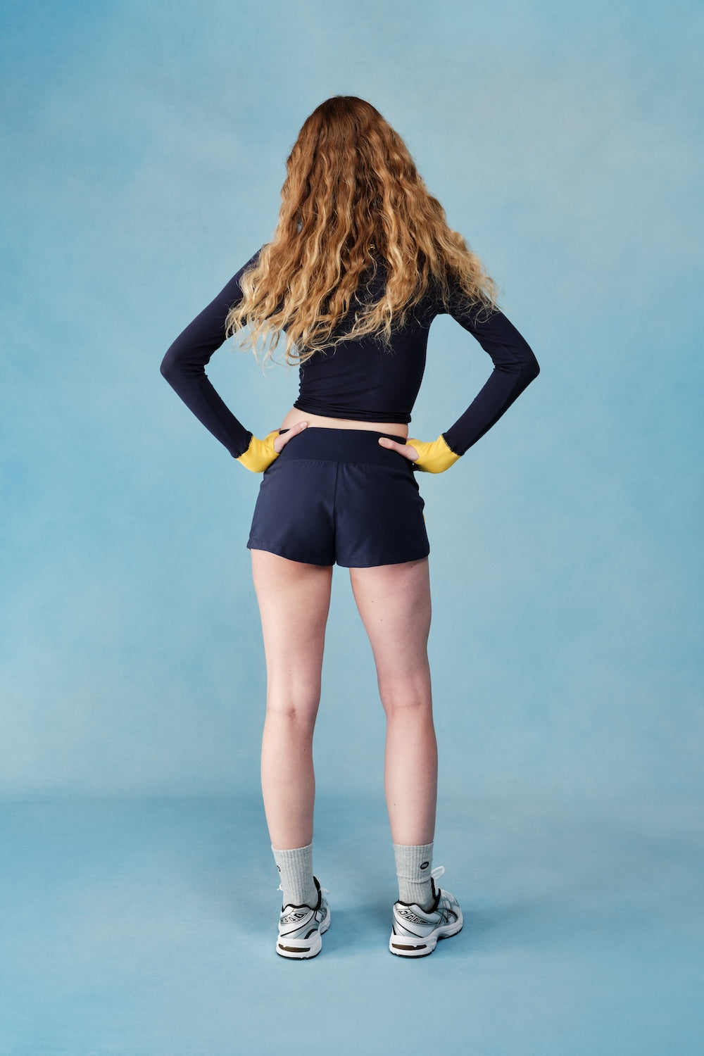 Person wearing a navy long-sleeve top and shorts on a blue background |M1
