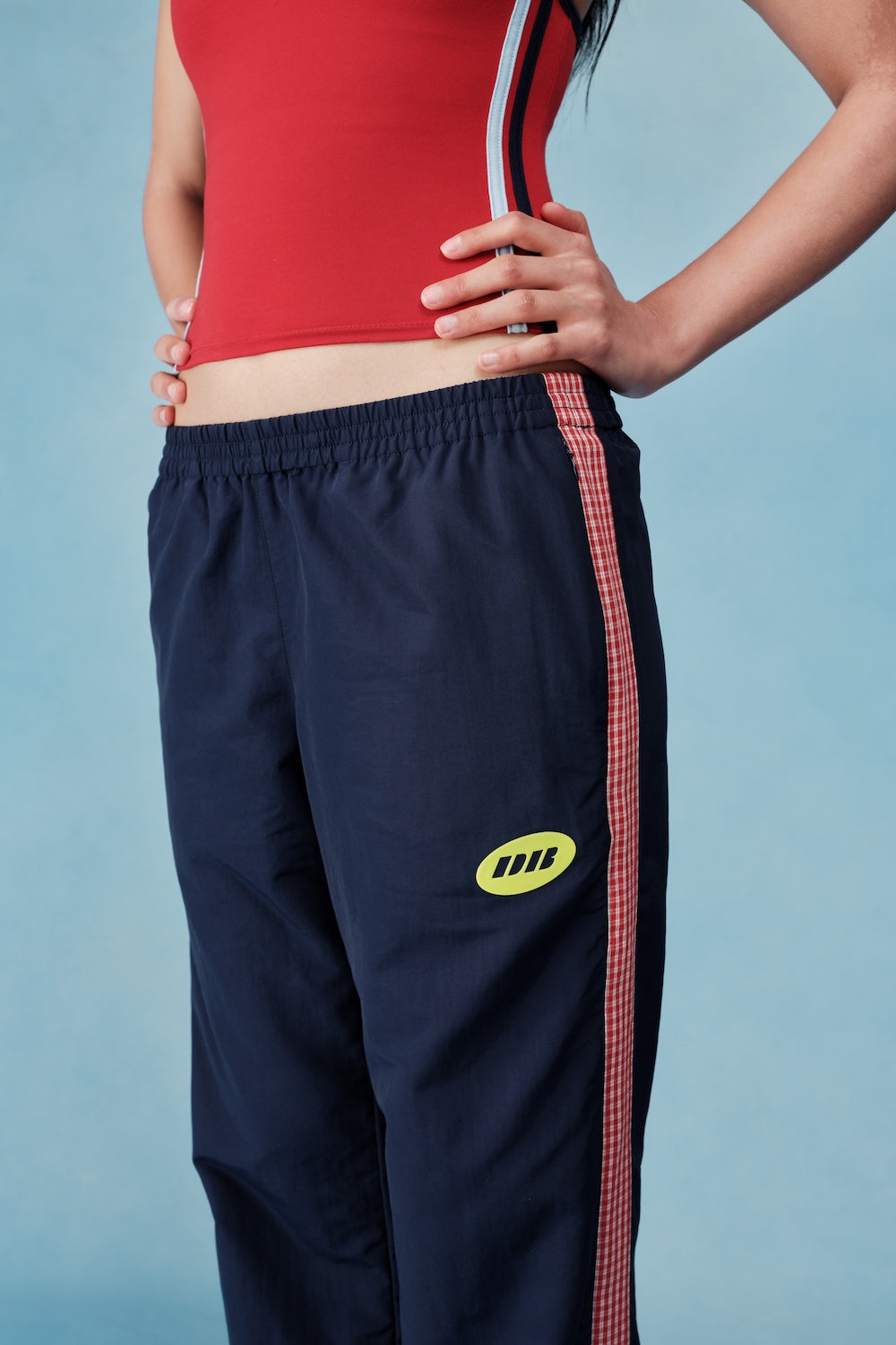 Navy tracksuit with red side panels and yellow logo on a blue background |M1
