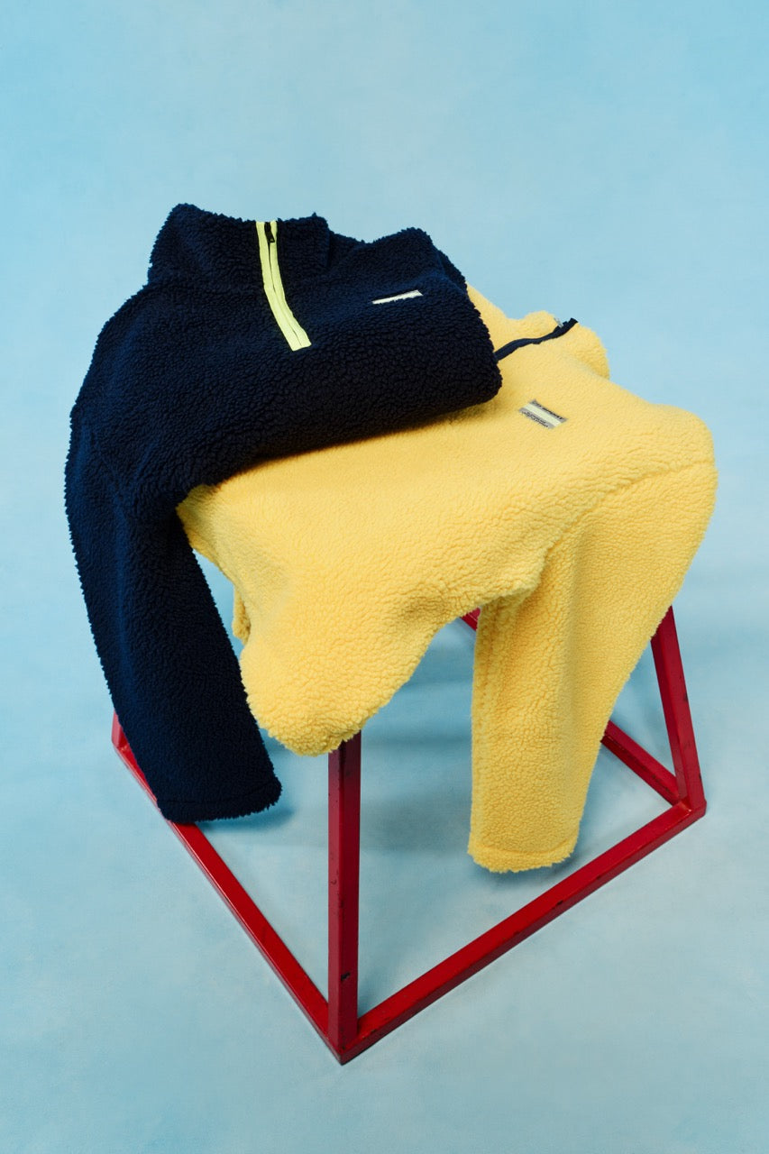 Navy and yellow fleece on a red stool against a light blue background