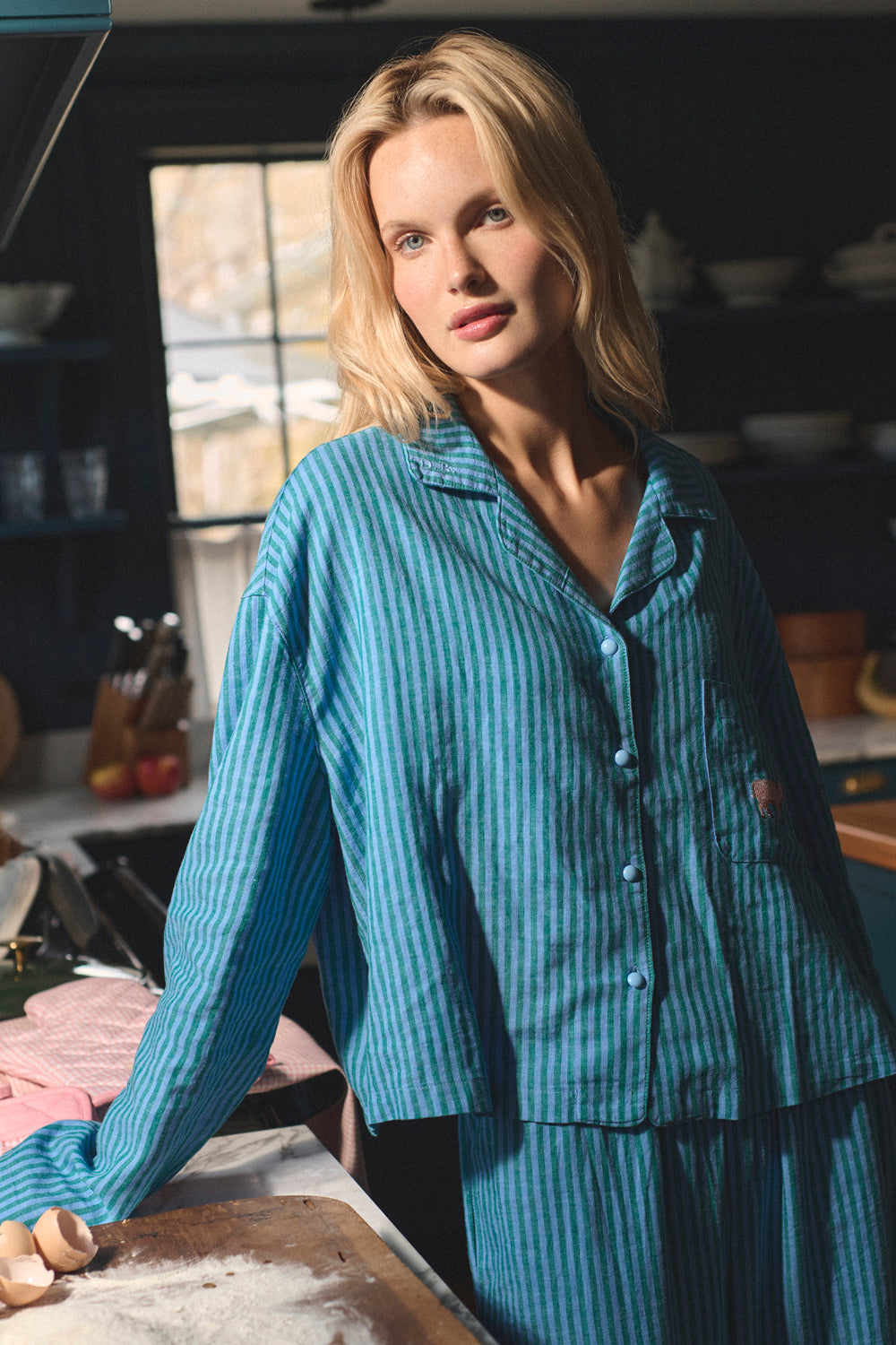 Woman wearing blue pajamas in a kitchen setting. |M1