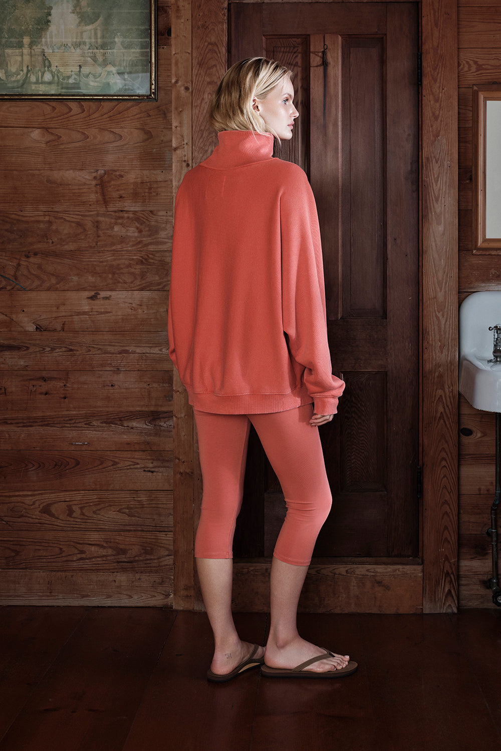 Person wearing a pink outfit standing in a rustic wooden interior.
|M1