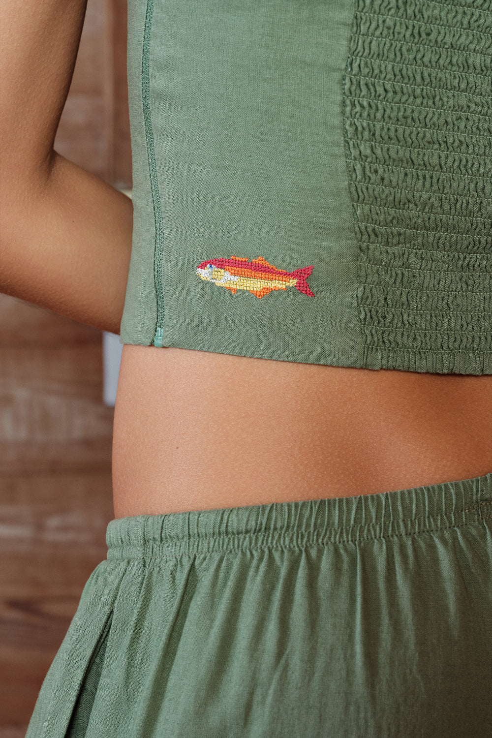 Green outfit with a fish embroidery detail on a blurred background
|M1