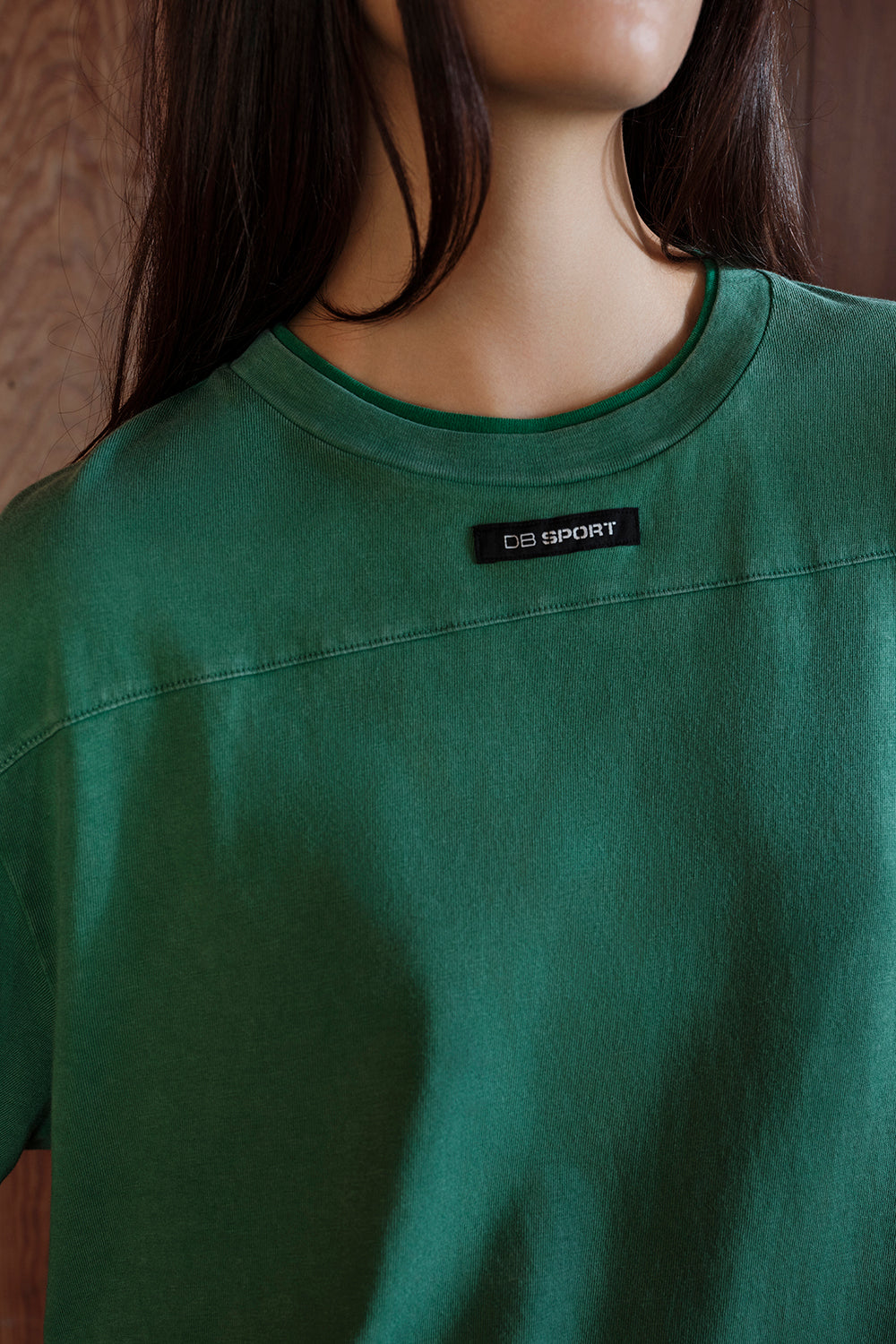 Green t-shirt with a brand label on a plain background
|M1