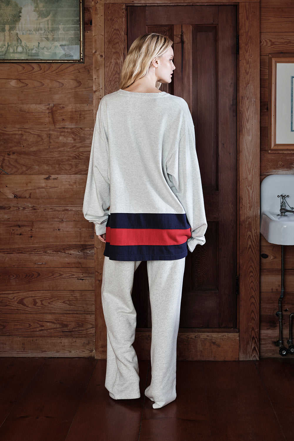 Woman wearing a light gray jersey in a wooden interior setting.
|M1