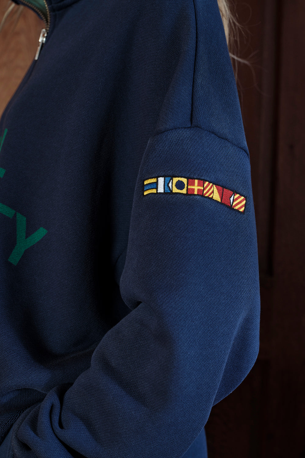 Navy blue sweatshirt with a colorful patch on the sleeve against a dark background
|M1
