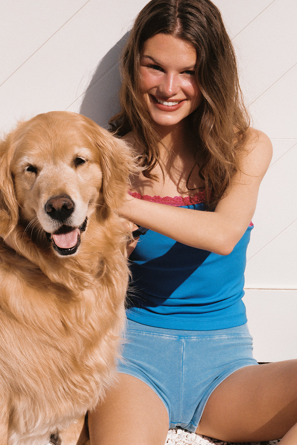 Woman sitting with a golden retriever on a white background