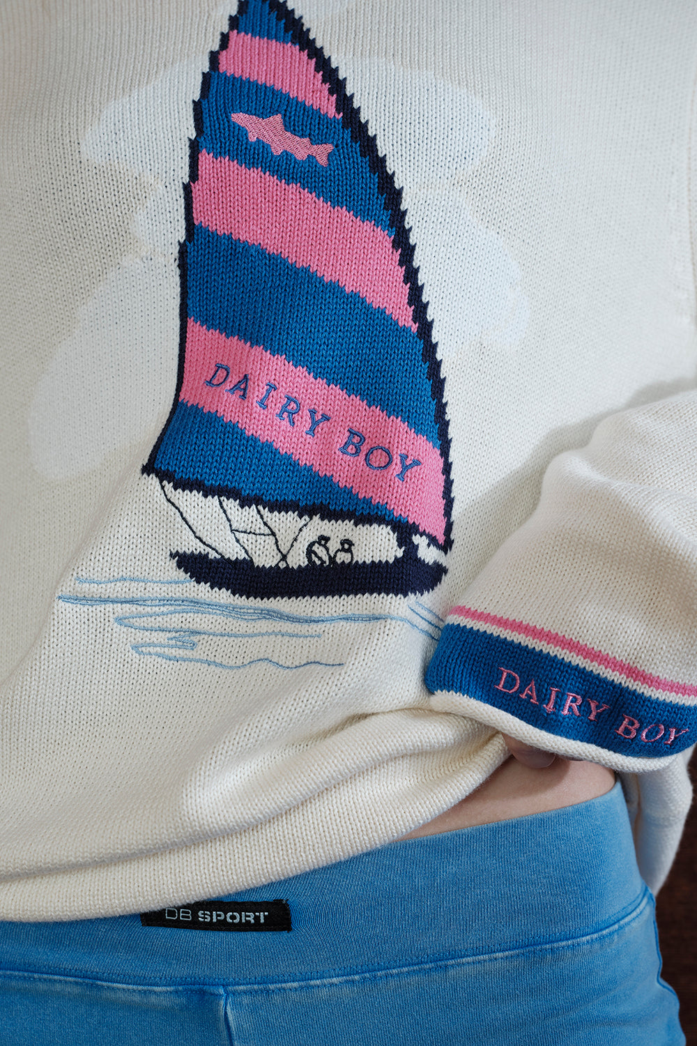 Close-up of a sweater with a sailboat design and 'Dairy Boy' branding.