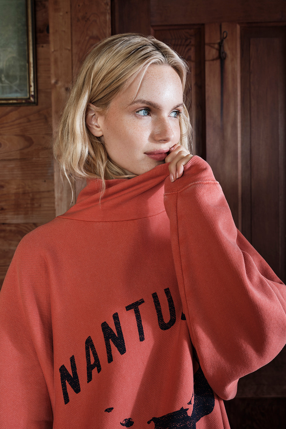 Woman wearing a red sweatshirt with 'Nantucket' text, indoors.
|M1