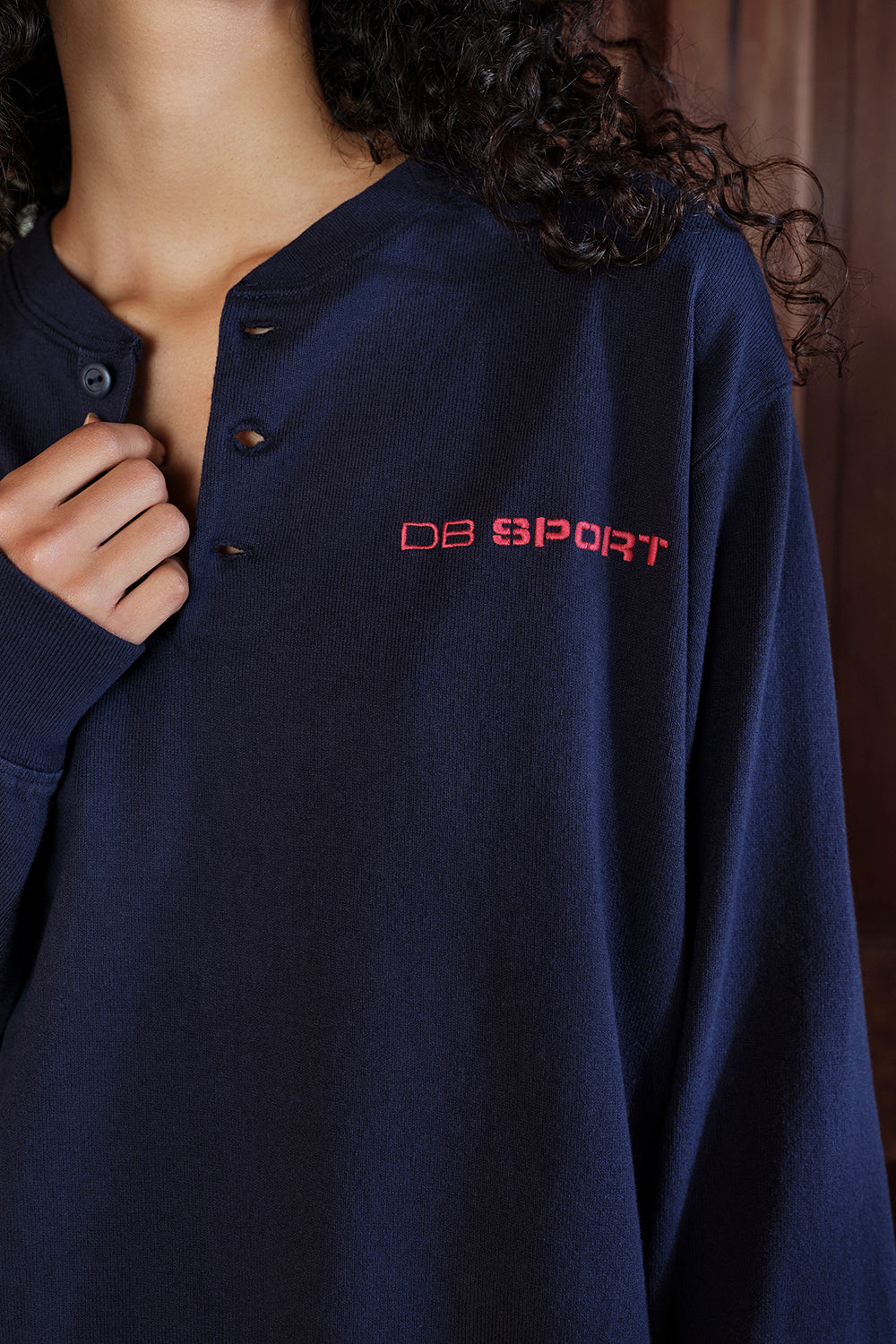 Navy blue shirt with red 'DB Sport' logo worn by a person
|M1