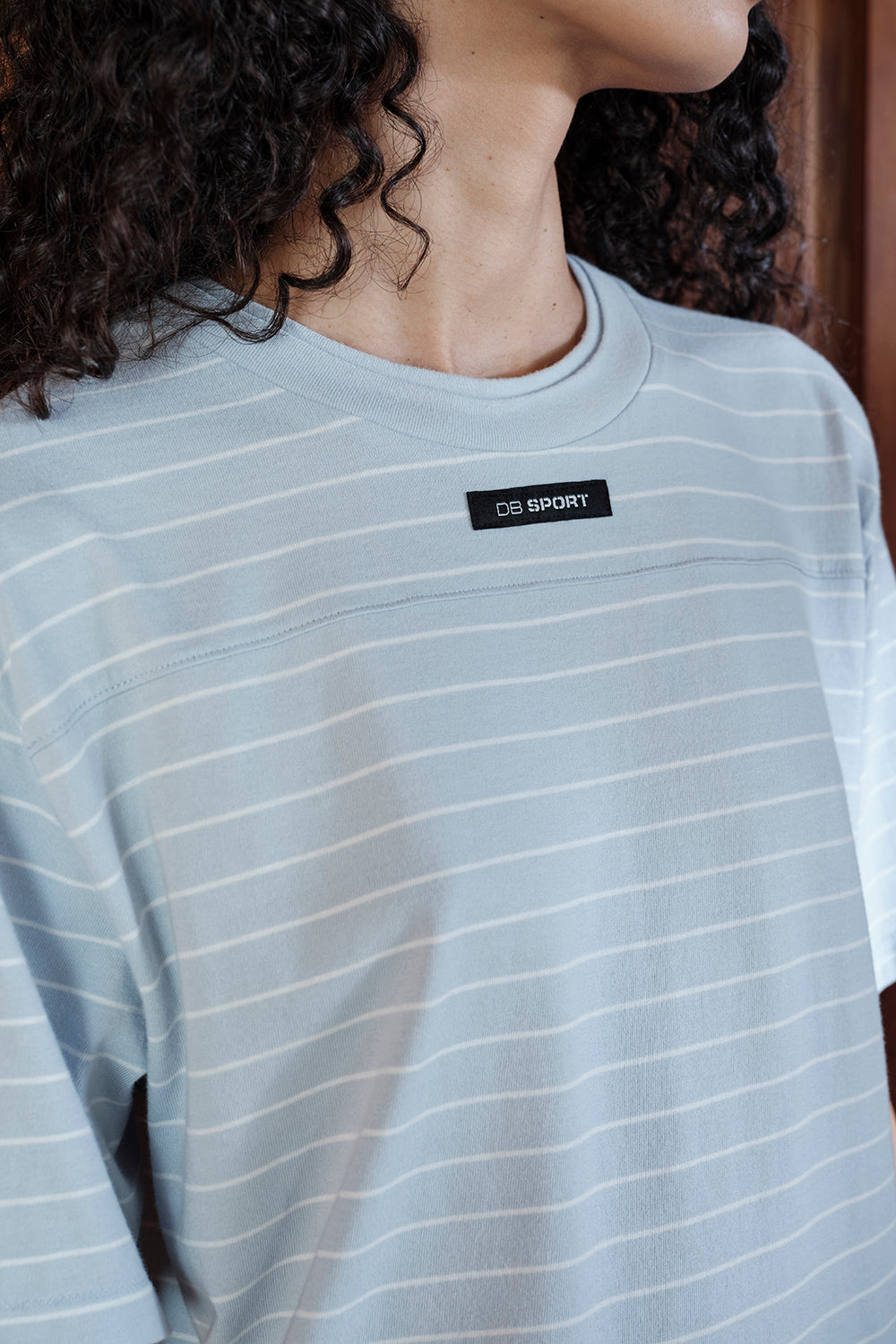 Person wearing a light gray long-sleeve shirt with a brand logo on the chest.
|M1
