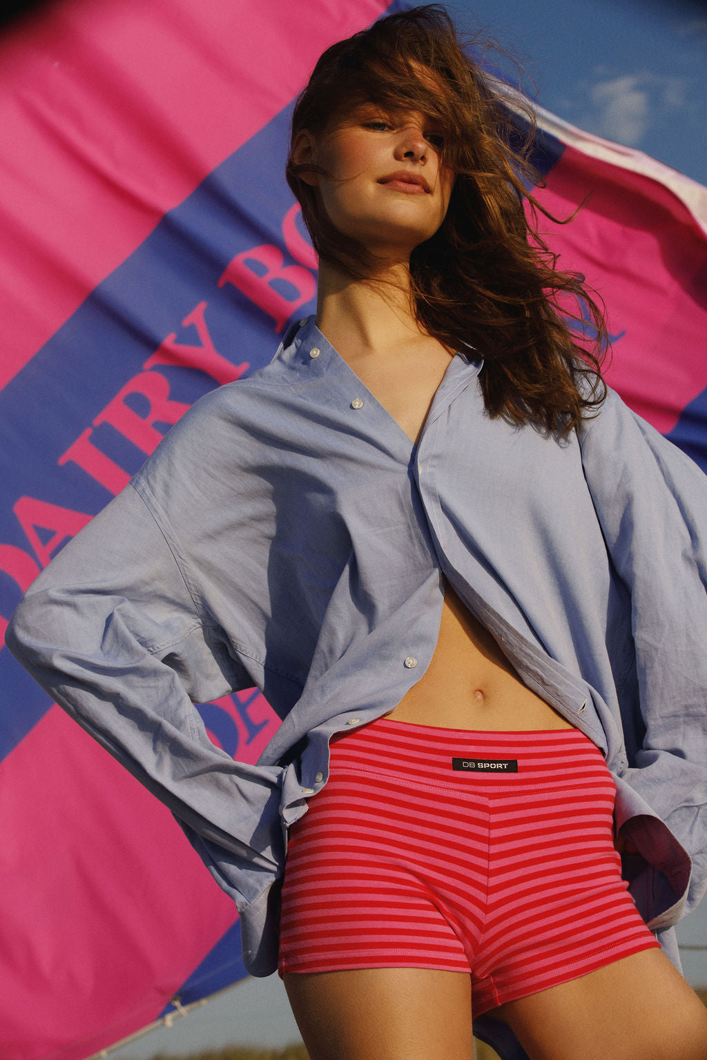 Woman wearing a light blue shirt and red striped shorts with a colorful background