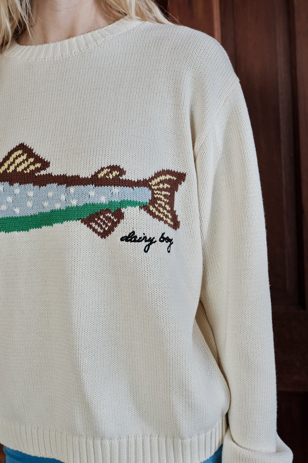 Close-up of a sweater with a fish design and 'dairy boy' text.
|M1