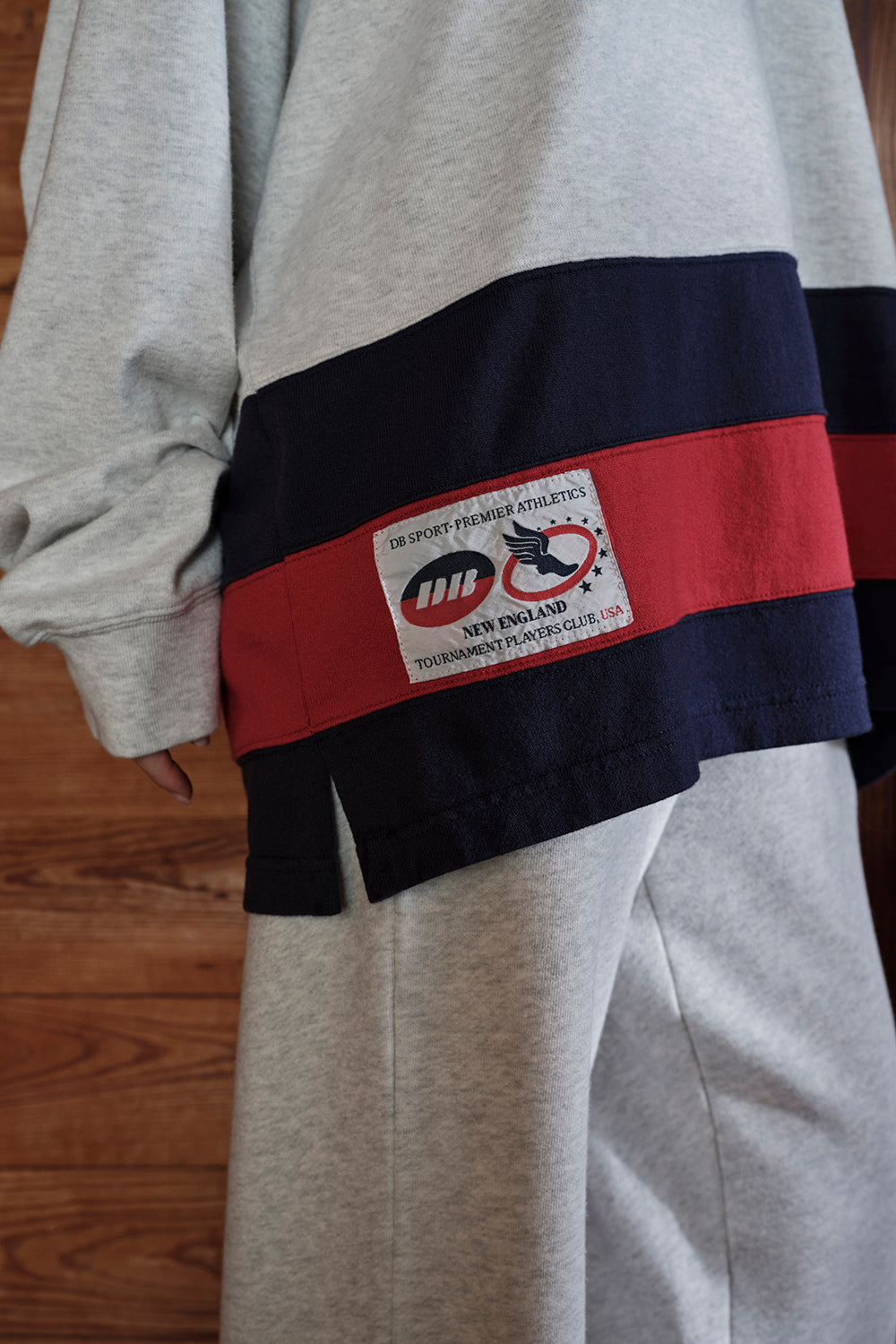 Gray sweatshirt with a colorful band and visible brand label on a wooden surface