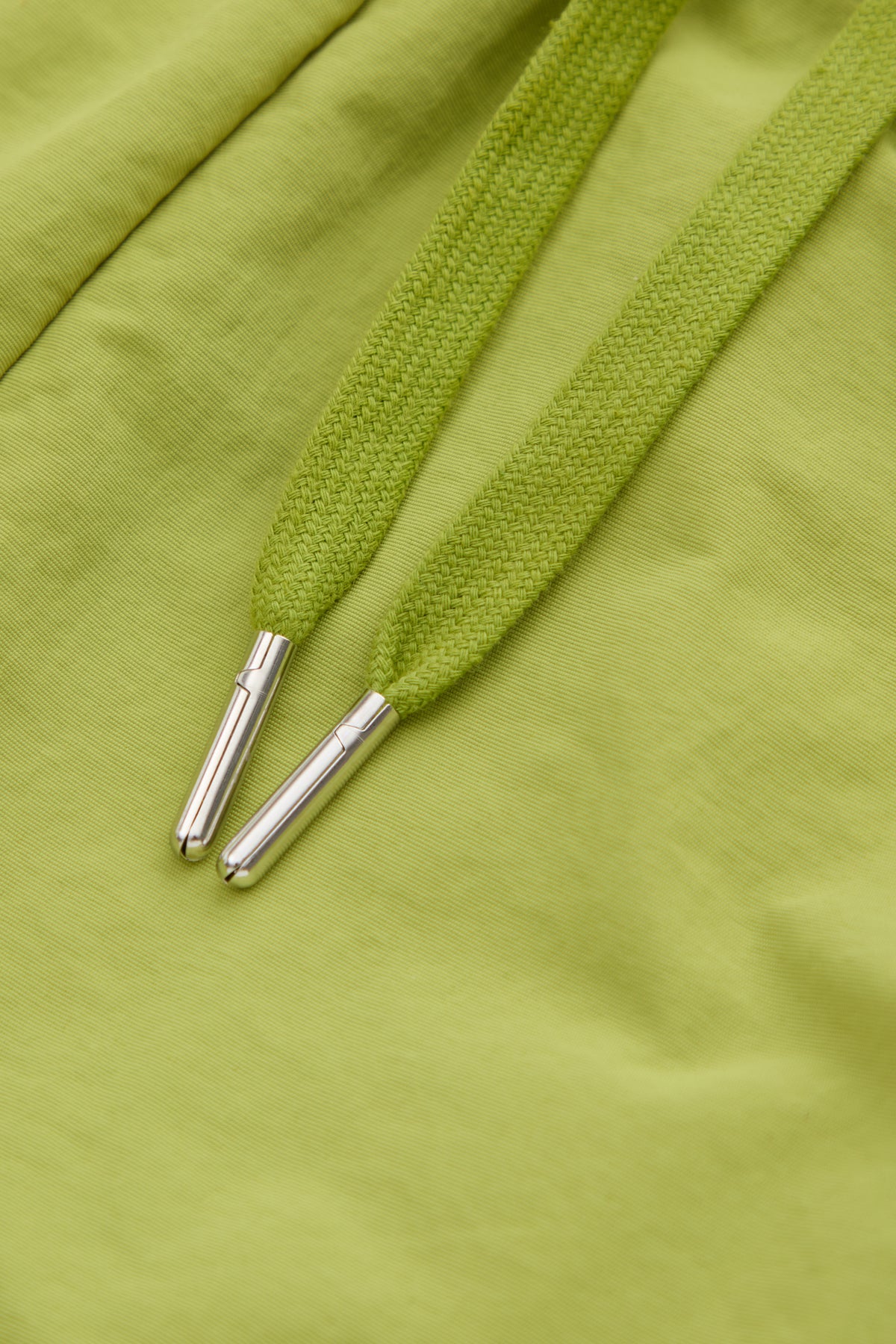 Close-up of green drawstring with metal eyelets on a green fabric shorts