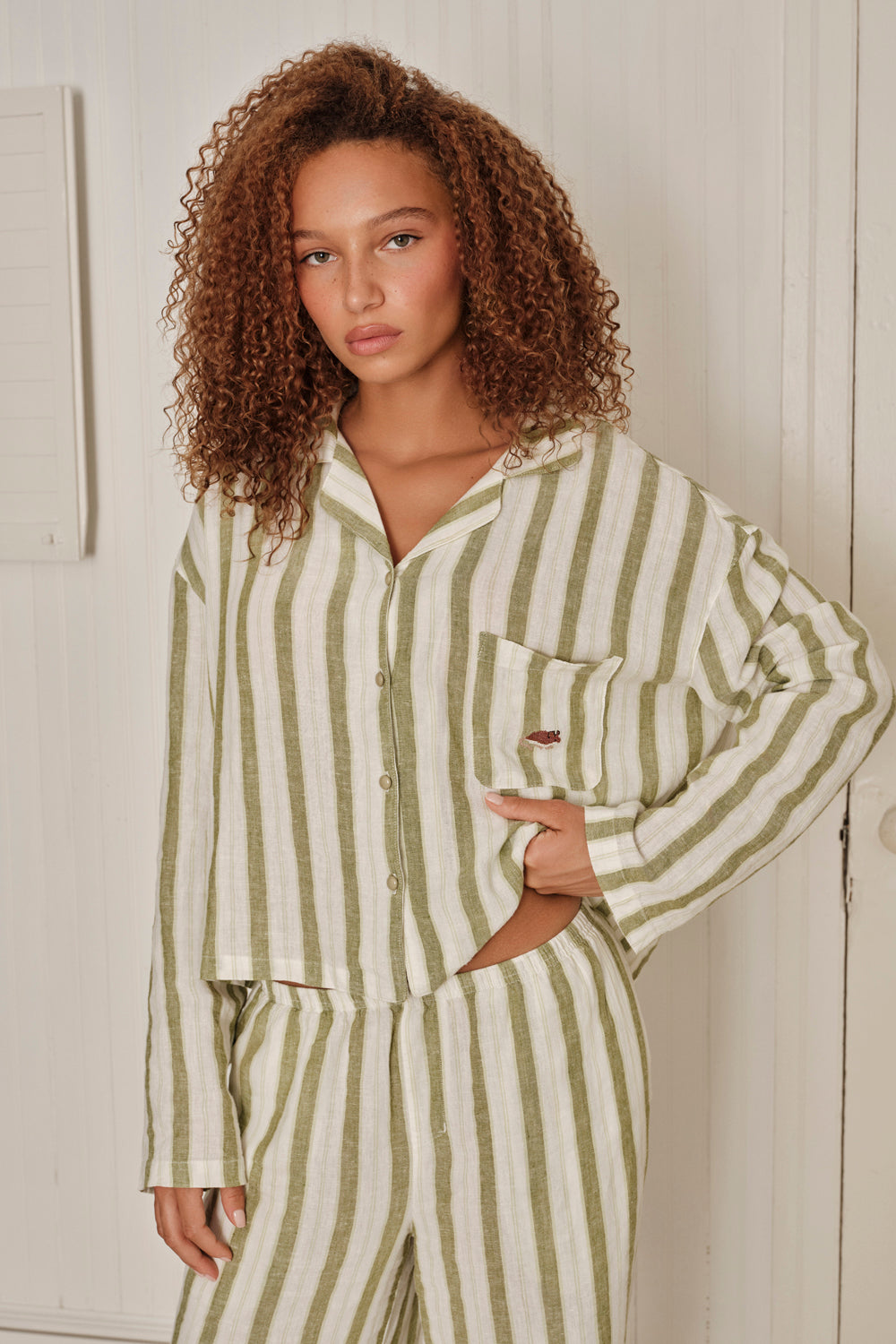 Woman wearing a green and white striped pajama set against a neutral background. |M1