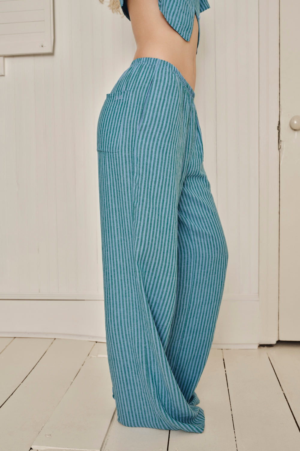 Person wearing blue striped pajama pants standing against a white wall. |M1