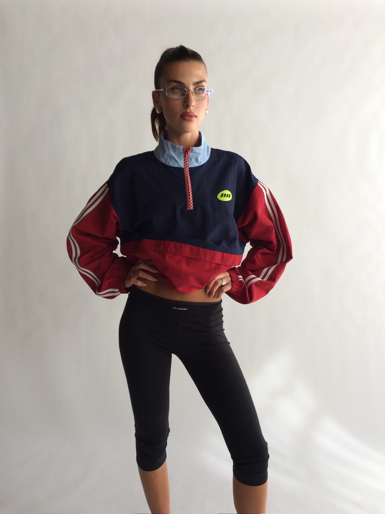 Person wearing a red and navy sports jacket with a logo on a white background |M1