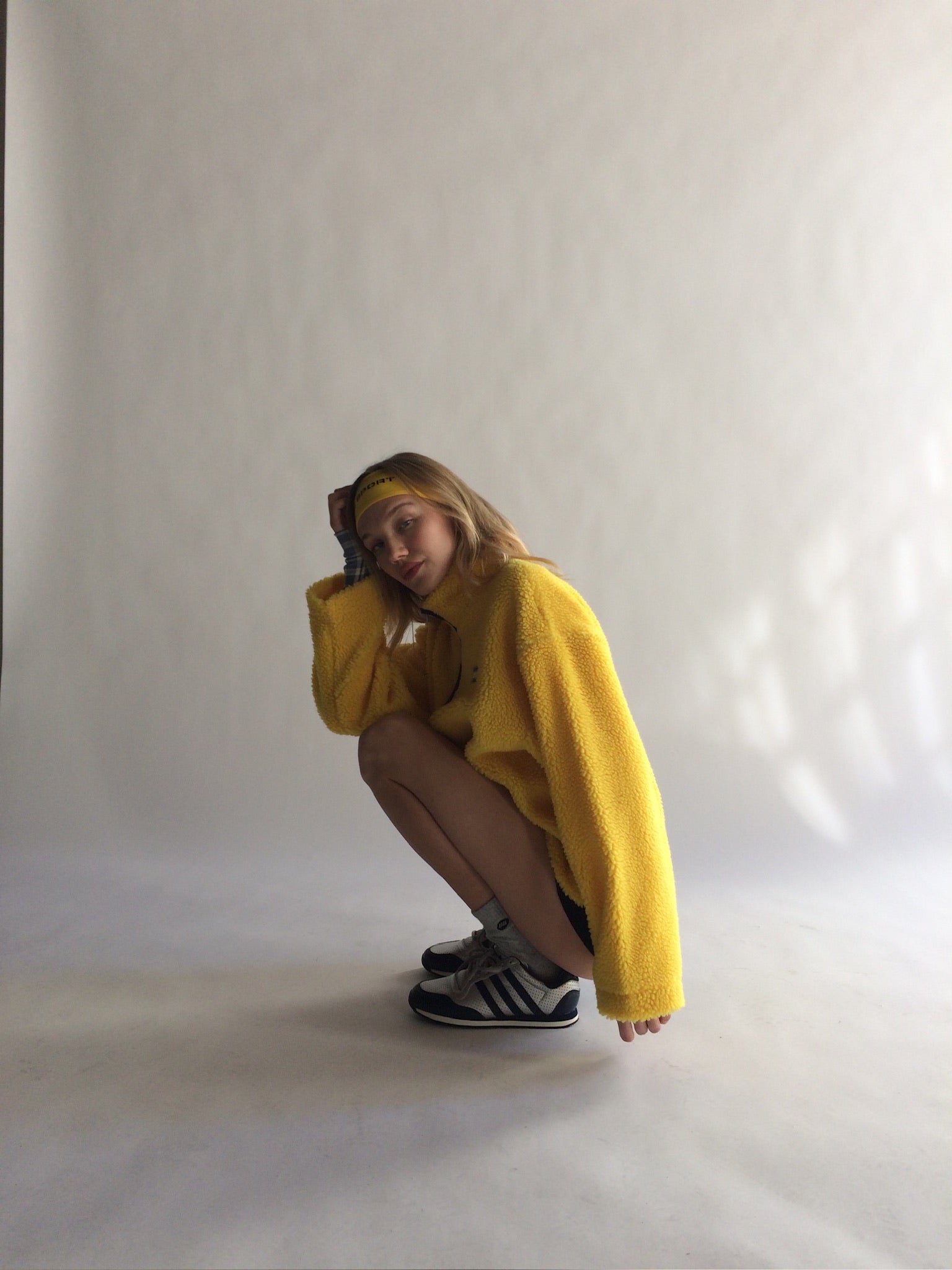 Person wearing a yellow fleece and black shoes on a white background |M1