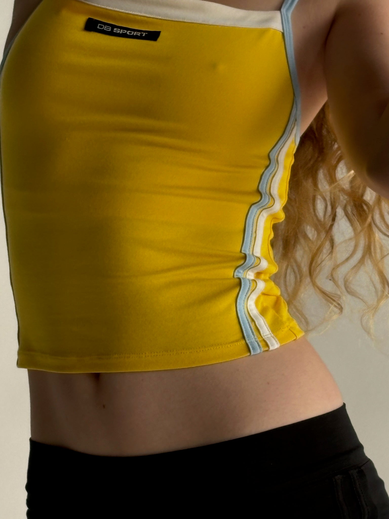 Yellow athletic top with a brand label on a neutral background |M1