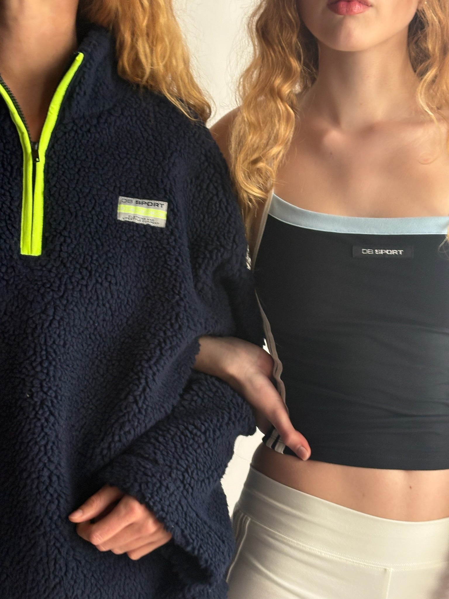 Two people wearing navy fleece and black sports bra with visible brand logos. |M1