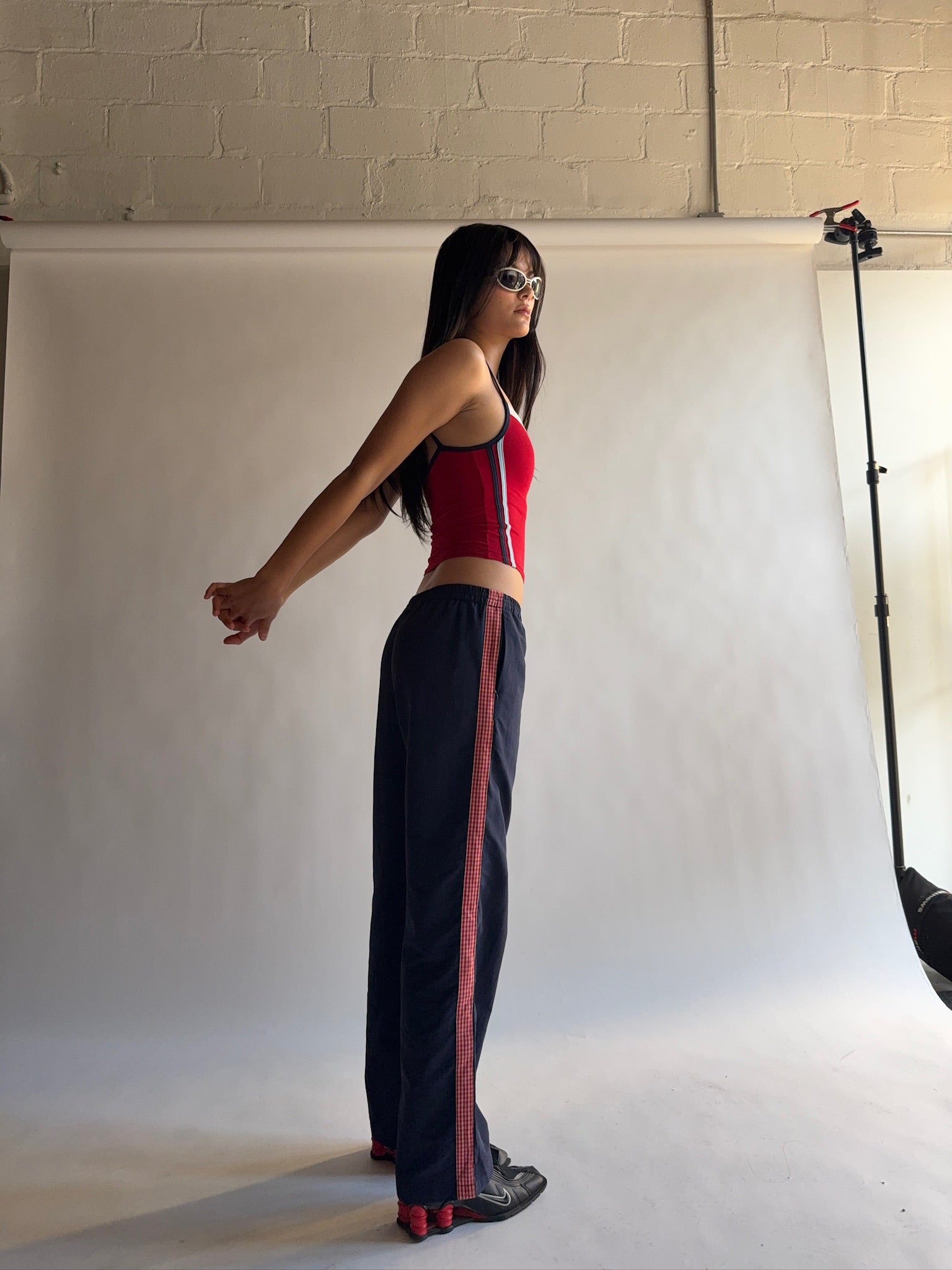 Woman in red top and black pants posing against a white backdrop in a studio setting. |M1