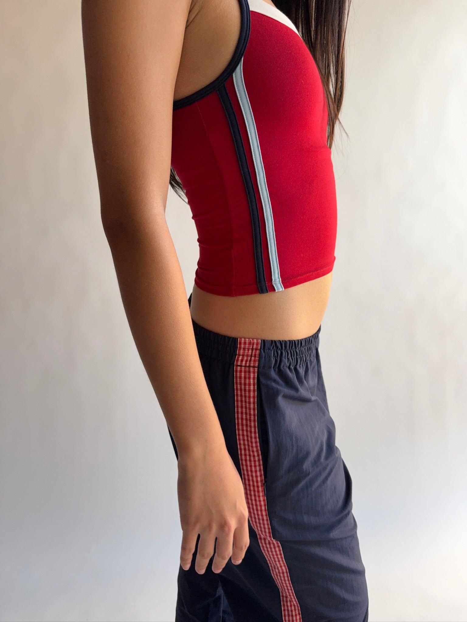Person wearing a red sports bra and black shorts with red stripes on a plain background |M1