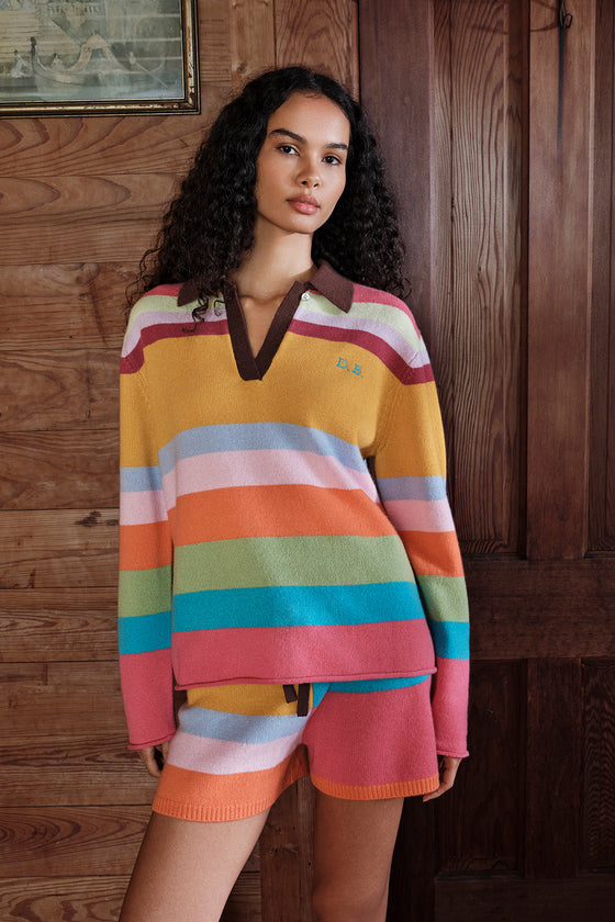 Woman wearing a colorful striped sweater and shorts against a wooden background
|M1