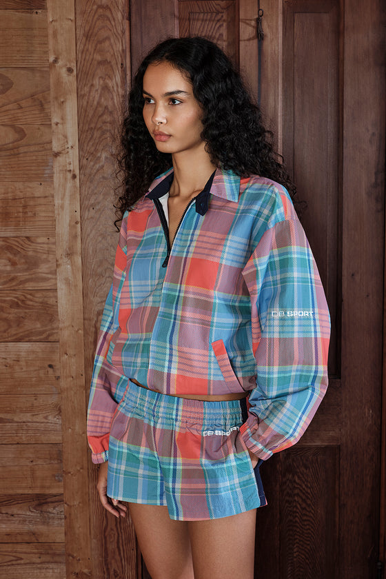 Woman wearing a plaid outfit with a visible brand logo against a wooden background
|M1