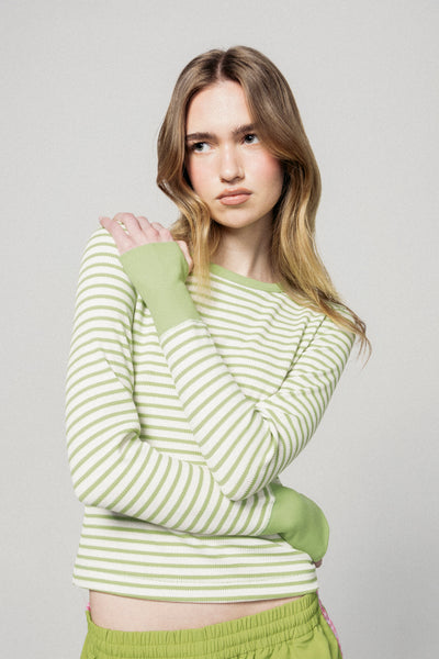 Woman wearing a green and white striped sweater with matching pants against a plain background |m1