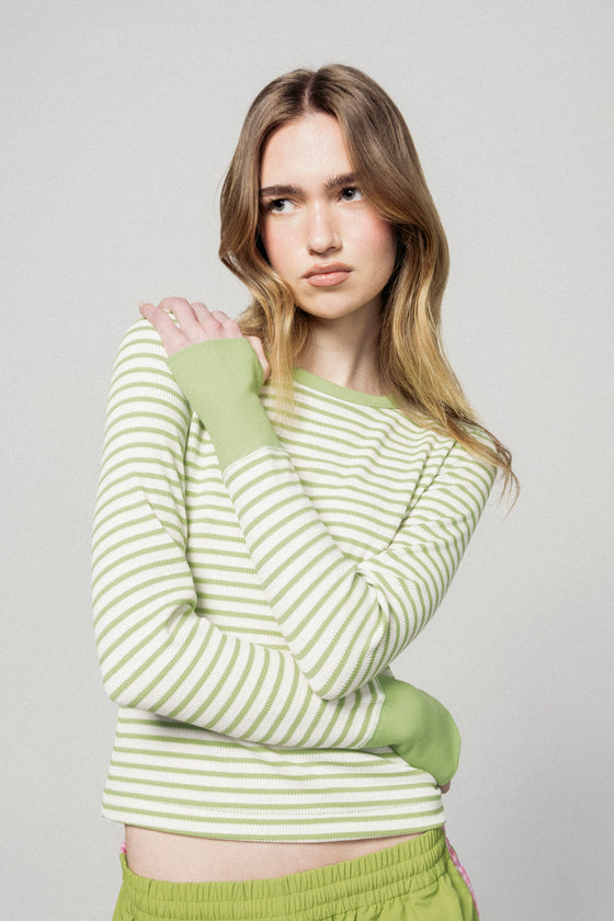 Woman wearing a green and white striped sweater with matching pants against a plain background |m1