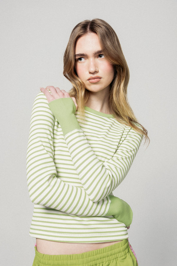 Woman wearing a green and white striped sweater with matching pants against a plain background |m1
