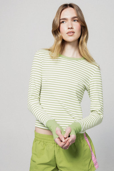 Woman wearing a green and white striped long-sleeve shirt and green pants against a plain background |m1