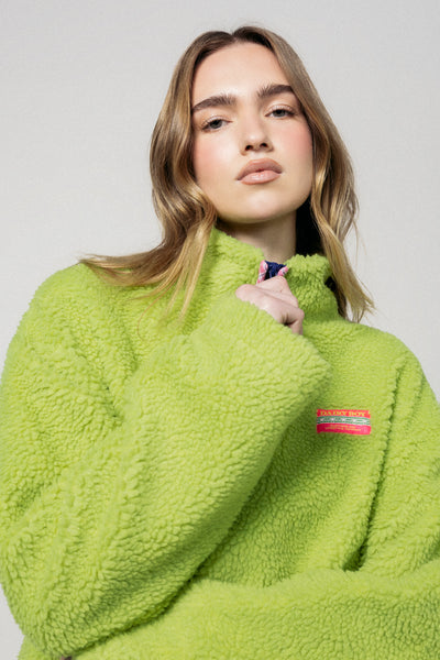 Woman wearing a bright green fleece jacket with a brand logo on a plain background |m1