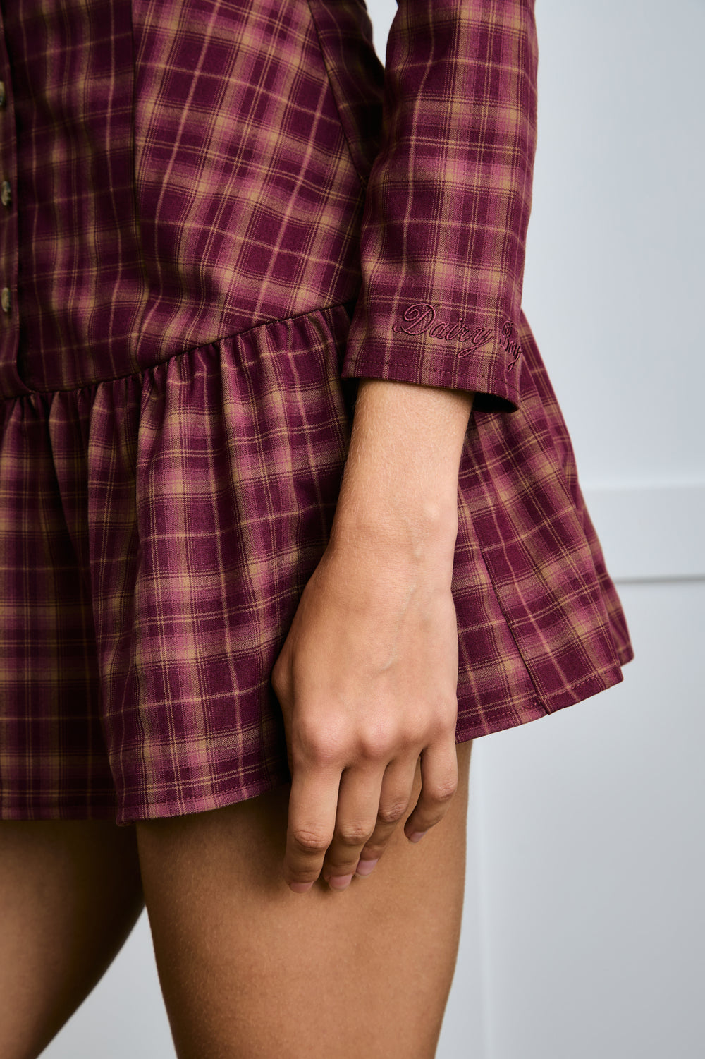 Close-up of a person wearing a plaid dress with an embroidery detail at wrist  |m1