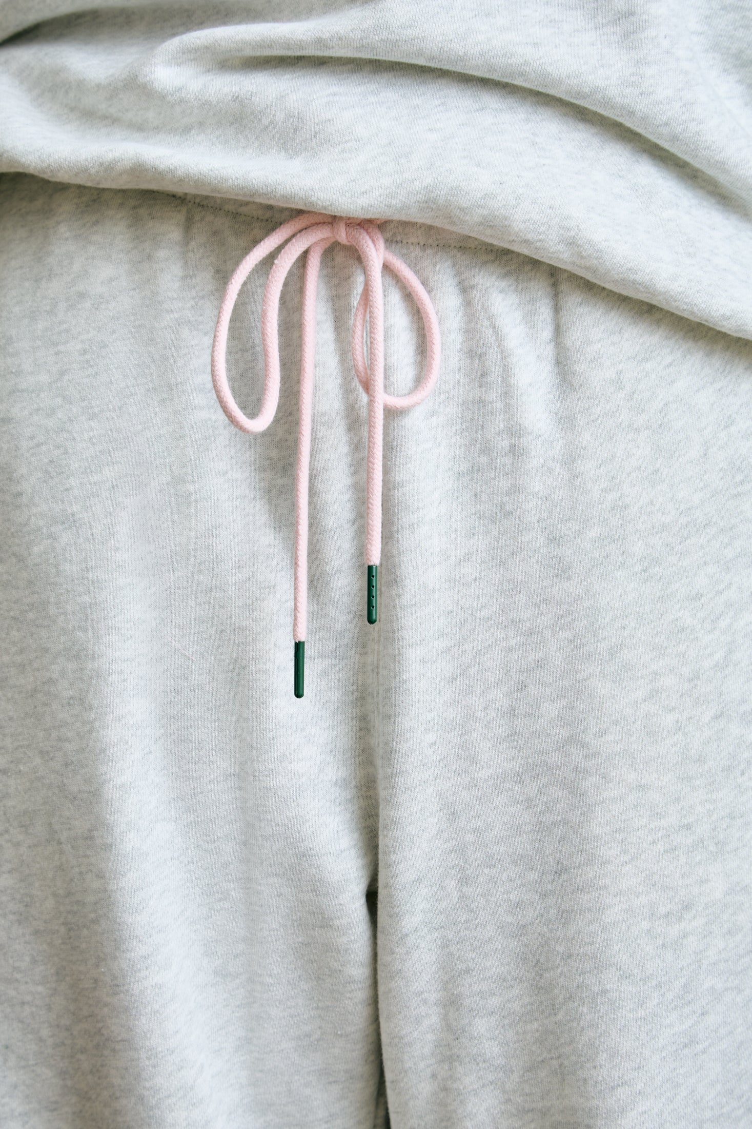 Light gray sweatpants with pink drawstring on a light gray background