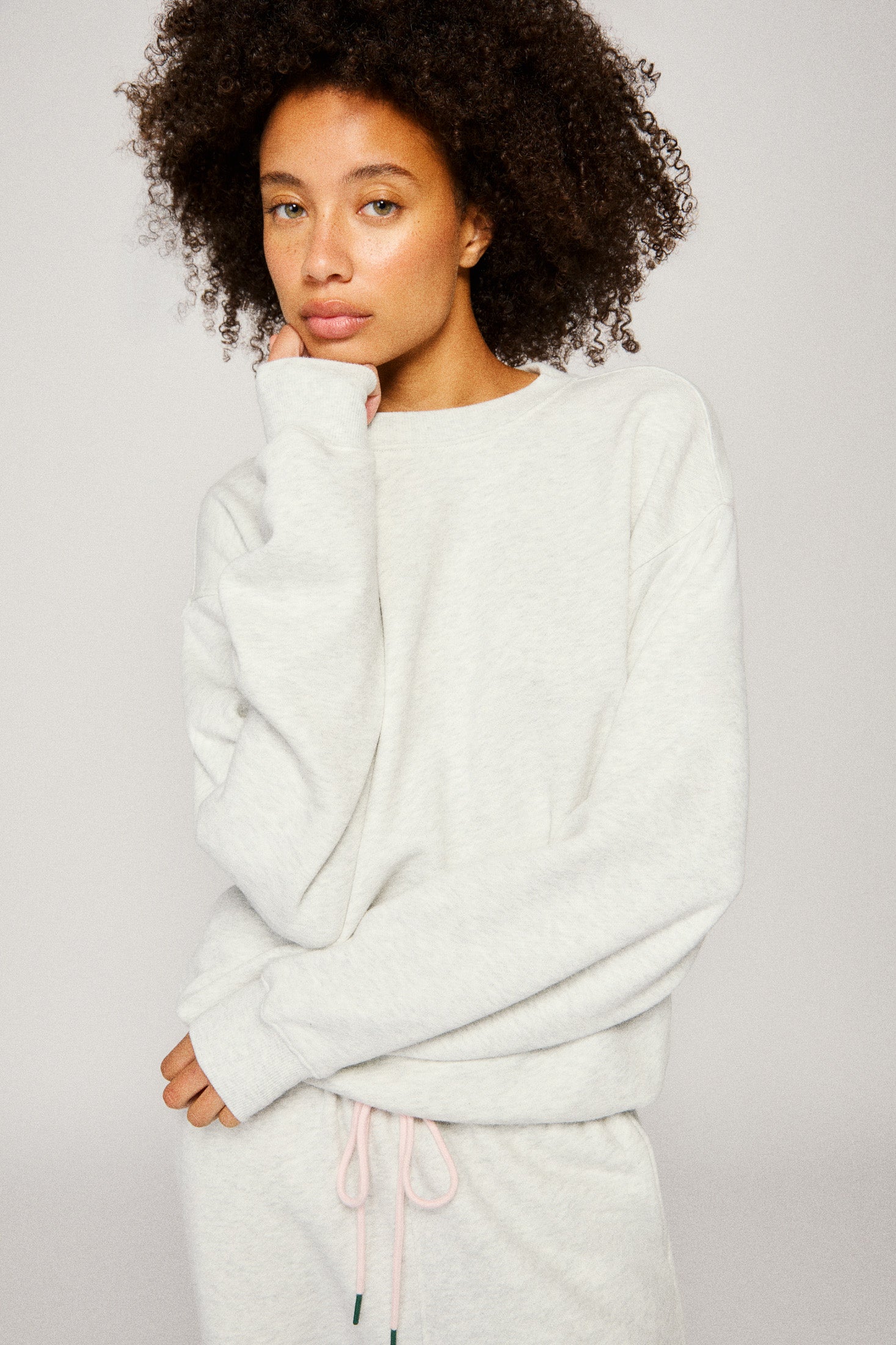 Woman wearing a light gray sweatshirt against a plain background |m1