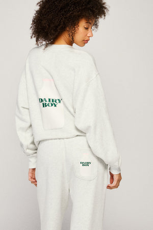 Person wearing a light grey sweatshirt and pants with 'Dairy Boy' branding on a plain background  |m1