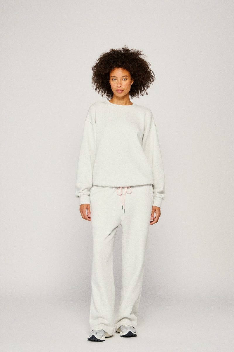 Person wearing a light gray sweater and sweatpants on a plain background |m1