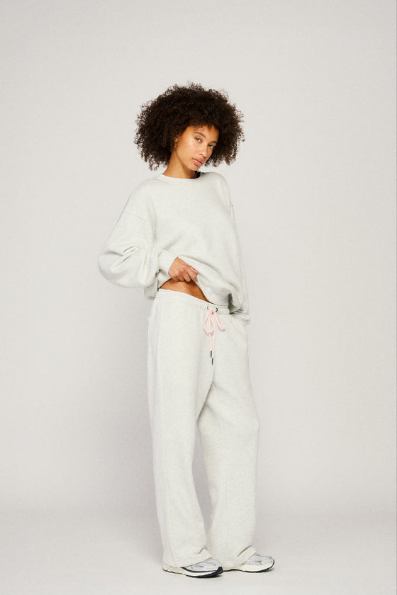 Person wearing a light grey sweatshirt and pants on a plain background |m1