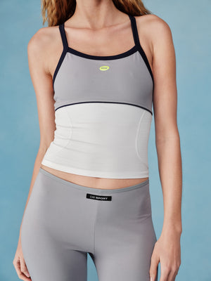 Woman wearing a gray sports tank and leggings with a blue background |M1