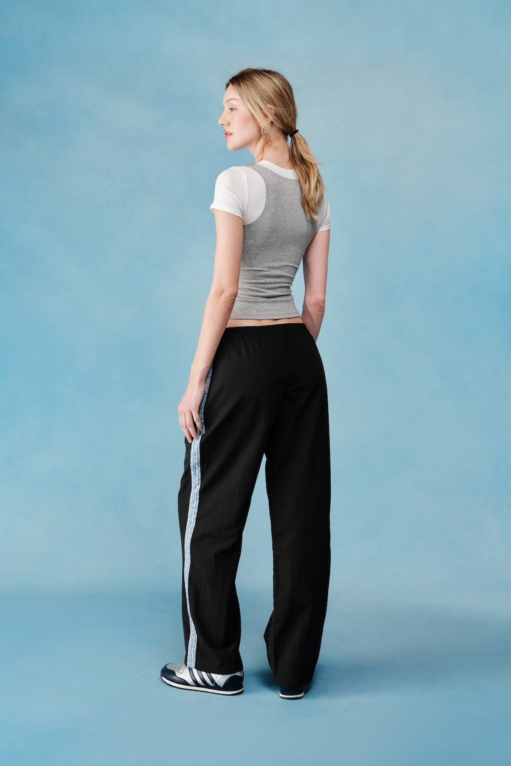 Woman wearing a gray top and black pants on a blue background |M1