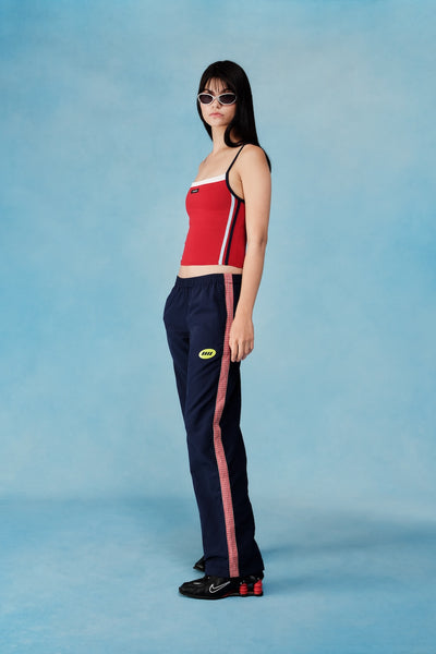 Person wearing a red top and navy pants with a red stripe on a blue background |M1