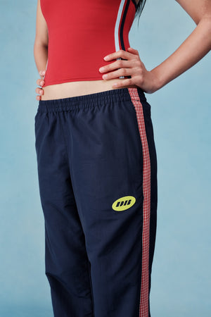 Navy tracksuit with red side panels and yellow logo on a blue background |M1