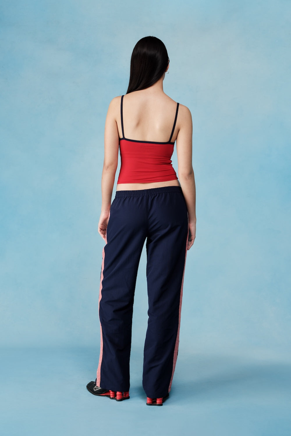 Woman wearing a red top and navy pants with red stripes on a blue background  |M1