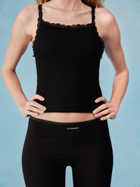 Black tank top with lace details worn by a person on a light blue background  |M1