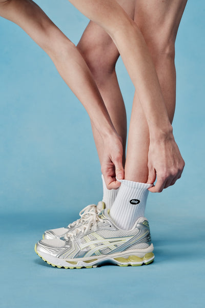 Person wearing white socks and gray athletic shoes on a blue background
